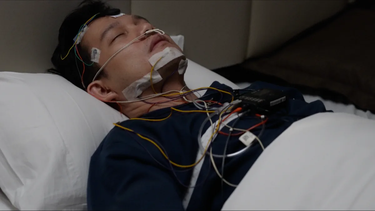 A patient asleep during an in-lab sleep study, wearing head, face and chest sensors